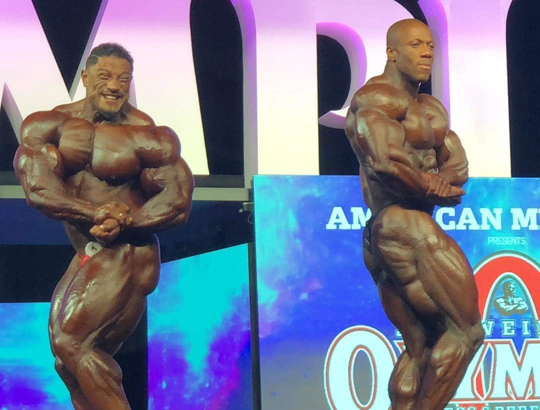 Brandon Hendrickson · Brandon Hendrickson and fellow finalists comparing back poses at the 2018 Men’s Physique Olympia